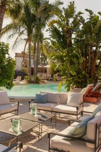 a patio with couches and tables in front of a pool at Masseria Messapia Wine Resort & Spa Salento in Mesagne