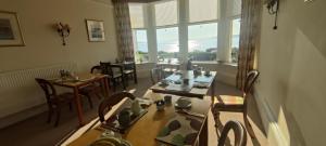 a dining room with tables and chairs and a large window at Douglas Park Guest House in Dunoon
