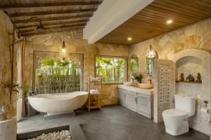 a bathroom with a tub and a toilet and a sink at Legong Sebatu Villa in Ubud