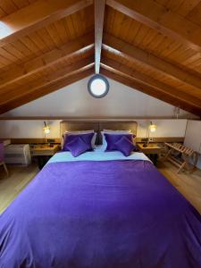 a large purple bed in a room with wooden ceilings at ARCHONTIKO Atsas - Amethystos in Kalymnos