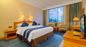 a hotel room with a large bed and a television at Kunming Hotel in Kunming