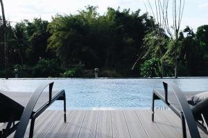 a wooden deck with two chairs next to a pool at Riverawan Hotel in Chanthaburi