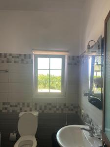 a bathroom with a toilet and a sink and a window at Hotel Luis in Durrës +9 photos
