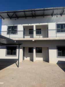a white building with a balcony on top of it at No75 Stays in Tlokweng