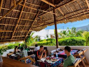 a group of people sitting at tables in a restaurant at Kendwa Crystal Coast Hotel in Kendwa