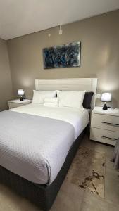 a bedroom with a large white bed with two lamps at No75 Stays in Tlokweng