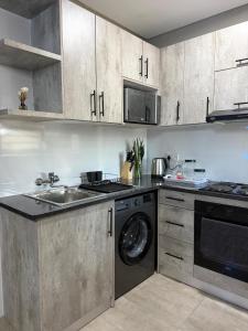 a kitchen with a sink and a washing machine at No75 Stays in Tlokweng