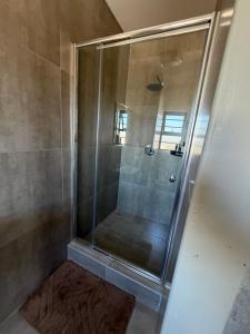 a shower with a glass door in a bathroom at No75 Stays in Tlokweng +6 photos