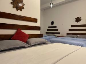 a room with three beds and a red pillow at Knuckles Retreat in Huluganga +3 photos