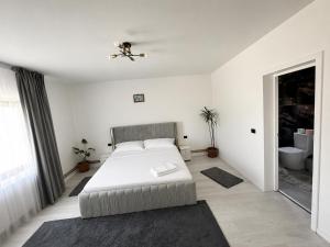 a white bedroom with a bed and a ceiling fan at A&D House in Novaci-Străini +29 photos