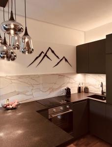 a kitchen with black cabinets and a stove and mountains on the wall at Mountain Loft Nassfeld in Tröpolach