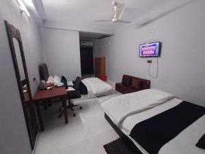 a room with two beds and a desk and a tv at Ostad Jahangir Resort in Cox's Bazar