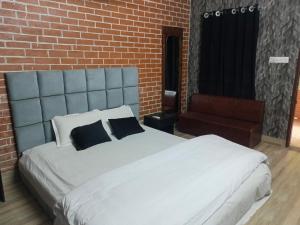 a bedroom with a large white bed with a brick wall at Ostad Jahangir Resort in Cox's Bazar +12 photos
