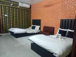 a room with three beds and a brick wall at Ostad Jahangir Resort in Cox's Bazar