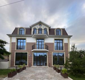 a large brick house with windows and a balcony at HIQ Hotel Home Inn Qusar in Qusar