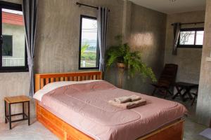 een bed met twee handdoeken in een slaapkamer bij Santitham Home Farm Stay in Mae Taeng