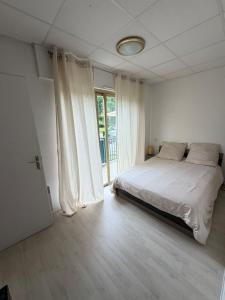 a white bedroom with a bed and a window at Appartement La Parenthèse Verte - Capvern in Capvern