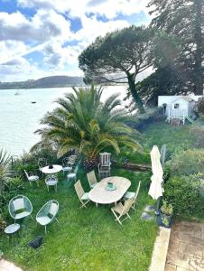a table and chairs on the grass next to the water at BB les pieds dans L'eau CARANTEC in Carantec
