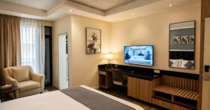 a hotel room with a bed and a desk and a television at Ras Hotel - Harar in Hārer