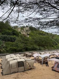 a bunch of tents on a beach with people walking around at camp asri in Bukittinggi