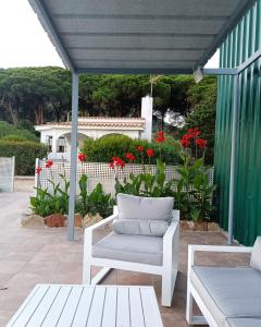 a patio with a white chair and red flowers at Finca Dos Vientos Tarifa in Tarifa