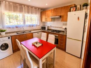 a kitchen with a red table and a white refrigerator at Casa Roda de Bará & Spa in Roda de Bará