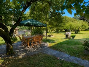 a table and chairs under an umbrella under a tree at Apartment Piccolo Borgo in Castelveccana