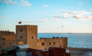 a building with a flag on top of it next to the ocean at Riad Le Cheval Blanc in Safi