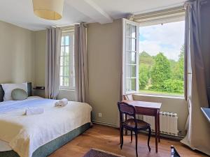 a bedroom with a bed and a desk and a window at Clos de Gauville in Brétigny
