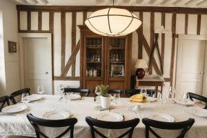 a dining room with a table with chairs and a chandelier at Clos de Gauville in Brétigny