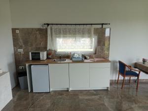 a kitchen with white cabinets and a sink and a window at Áporka vendégház in Áporka