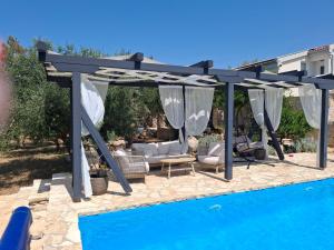 a pergola next to a swimming pool next to a house at Opg Pelejš in Pag