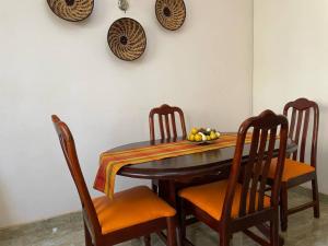 a wooden table with chairs and a bowl of fruit on it at Mukisa Apartments in Kampala