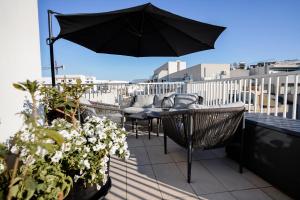 a patio with a table and an umbrella on a balcony at Central Penthouse with massive terrace in San Ġwann