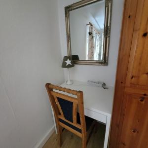 a mirror over a white desk with a wooden chair at Ferienwohnung Auszeit in Hohnstein
