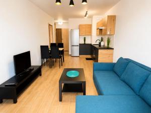 a living room with a blue couch and a kitchen at Apartament Dolina Baryczy in Żmigród