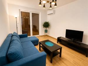 a living room with a blue couch and a tv at Apartament Dolina Baryczy in Żmigród
