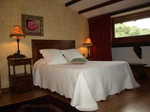 a bedroom with a white bed with two lamps and a window at Posada El Salin in Muñorrodero
