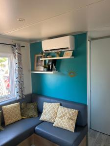 a living room with a blue couch with pillows at camping les oyats in Seignosse