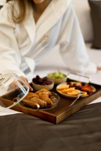 a woman is holding a tray of food on a table at Xhasen Hotel & Café in Tirana