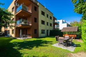 an apartment building with a table and chairs in the yard at AH-Corso Wellness Residence in Siófok