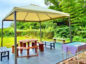 a patio with a canopy and picnic tables and a glass table at ラシェール 伊豆 ガーデンテラス AWA Resort in Ito