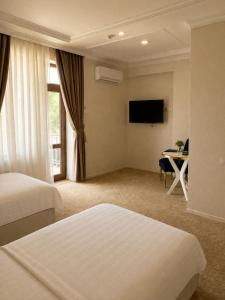 a hotel room with two beds and a table and a television at HUMO PLAZA in Fergana