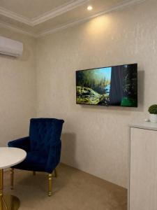 a room with a blue chair and a tv on a wall at HUMO PLAZA in Fergana