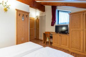 a bedroom with a bed and a desk with a television at Hotel Castel Pietra in Fiera di Primiero
