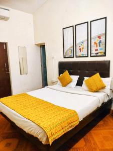 a large bed with yellow pillows in a room at Baga Beach Way in Baga