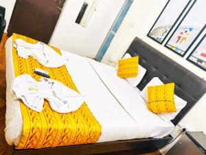 a bed with yellow and white sheets and yellow pillows at Baga Beach Way in Baga