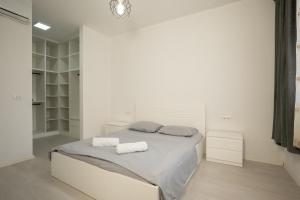 a white bedroom with a bed with towels on it at MaisonNova Deluxe 2 in Tirana
