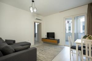 a living room with a couch and a table and a tv at MaisonNova Deluxe 2 in Tirana