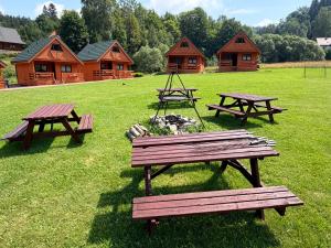 a group of picnic tables in a field with log cabins at Domki na Podgórzu in Duszniki Zdrój